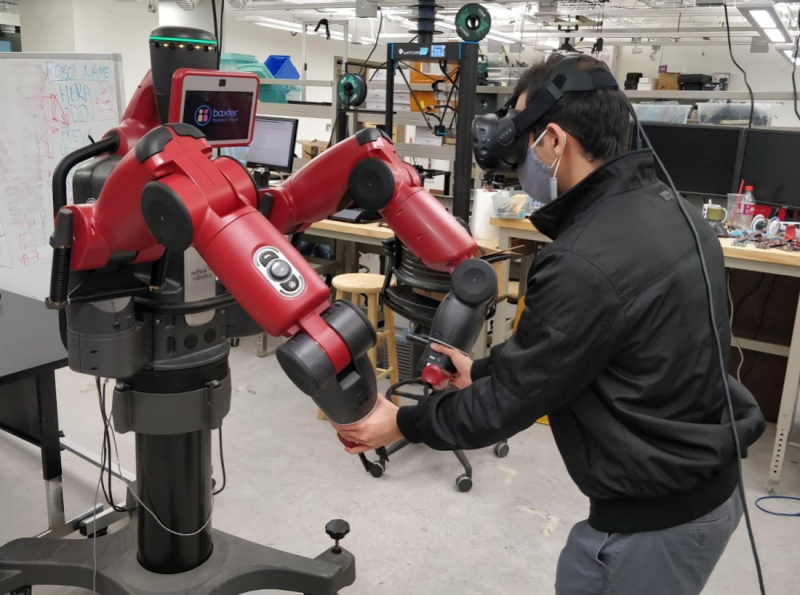 OEB lab researcher moving robotic arms while wearing VR headset